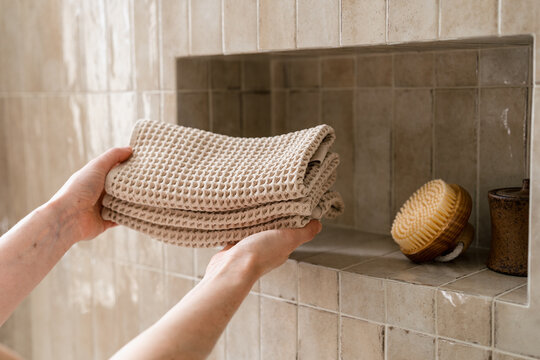 Holds towels in a bathroom during morning hygiene routine by the shower