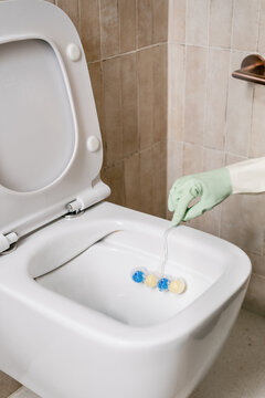 Cleaning a toilet bowl in a restroom with disinfecting tools and gloves