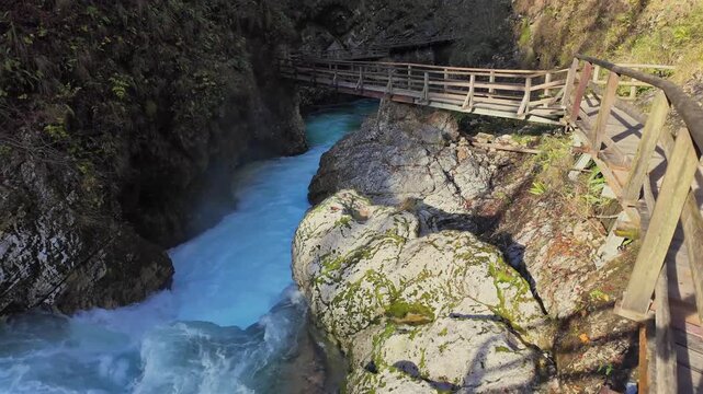Scenic view of Vintgar Gorge in Slovenia, where the turquoise Radovna River flows through the canyon next to a wooden walkway