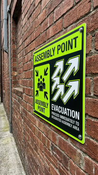 Assembly Point Evacuation Sign On Brick Wall Safety Instruction