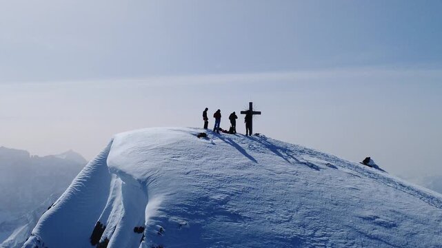 Gipfelkreuz im Gegenlicht mit Skitourengruppe &ndash; goldene Stimmung und lange Schatten im Schnee