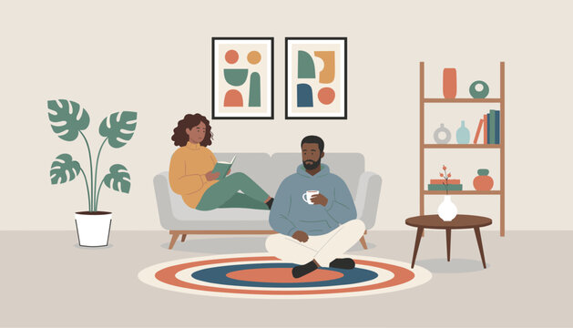 Black couple enjoys a quiet afternoon in their cozy living room with one reading a book and the other drinking coffee.