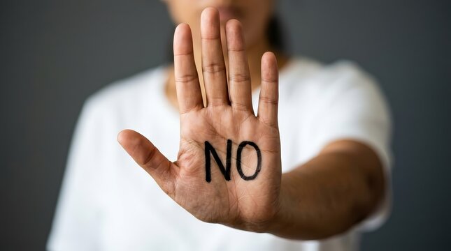 A woman's hand held up with the word NO written on the palm.