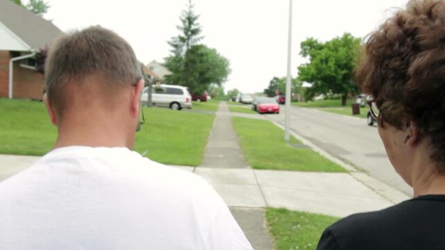 Couple holding hands walking down sidewalk
