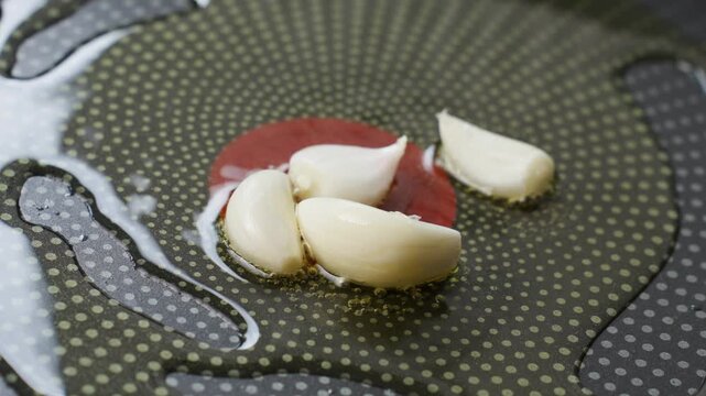 Peeled garlic cloves fry in hot oil in pan. Preparing aromatic ingredients for homemade cooking