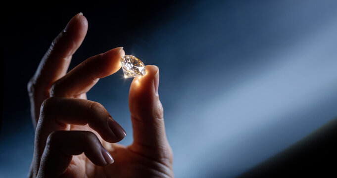 A large diamond gemstone is held in a firm hand.