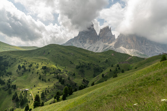 Italy, Sassolungo mountain landscape with green alpine hills and dramatic clouds