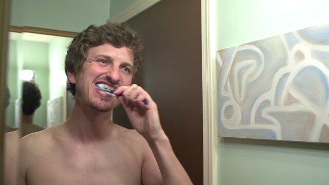 Young male brushing teeth in bathroom
