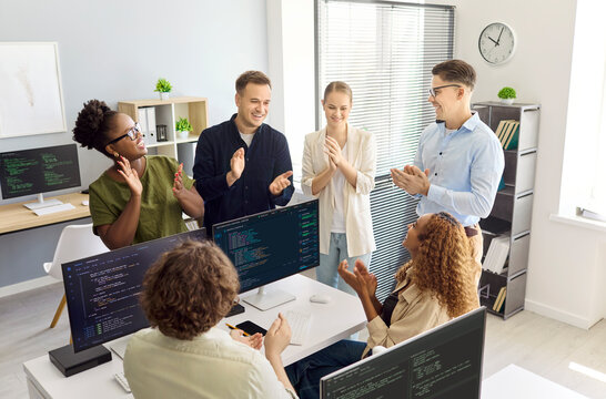 Developers team programmers applauding colleagues in office. They celebrate coding success, marking a startup milestone and teamwork in a workspace. Clear concept of teamwork and celebration.