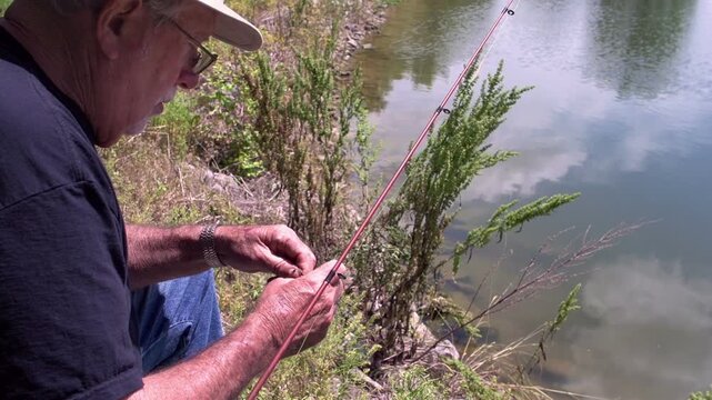 Elderly man baiting hook while fishing
