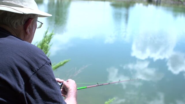 Man fishing in pond on sunny day
