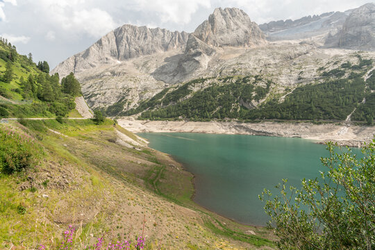 Canazei, Italy. Lago di Fedaia with low water level and exposed shoreline beneath the Marmolada mountain range