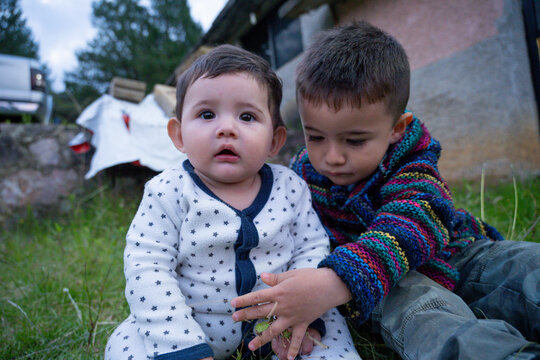 Close-up portrait of two brothers interacting outdoors in a green garden.