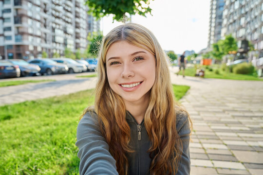 Young attractive woman taking a selfie outdoors in modern city street on sunny summer day