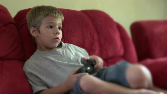 Child playing video game sitting on couch
