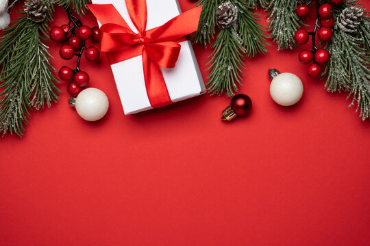 Red and white Christmas decorations and gifts on red background.