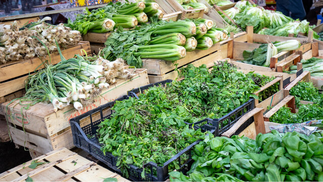 Fresh Green Vegetables and Herbs Displayed in Wooden Crates at Farmers Market