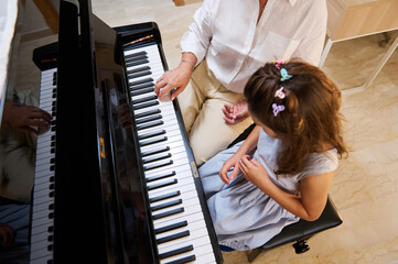 Woman piano teacher giving a piano lesson to a young girl at home © Taras Grebinets