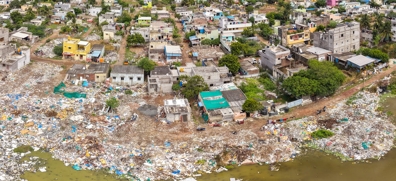 Garbage and plastic waste choking the edge of a crowded city settlement