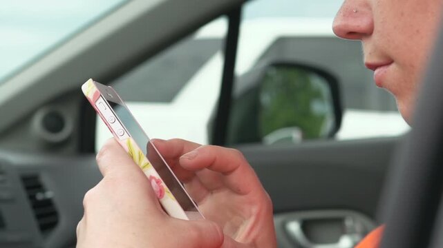 Female browsing smart phone sitting in car
