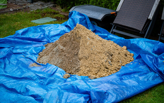 Excavated soil and sand stored on blue tarpaulin