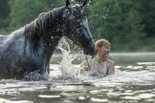 Frau badet mit Pferd im See