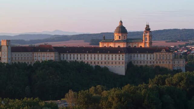 Melk Abbey in Austria, with a beautiful sunrise illuminating the historic Baroque abbey church and its magnificent architecture.