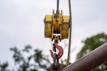 Selective focus on a metal crane hook lifting a heavy boom, with industrial details fading into a softly blurred background. © yackers1