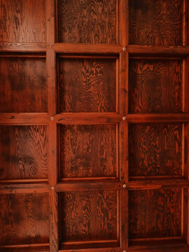 Dark wooden coffered ceiling with geometric panels and ornate decorative rosettes