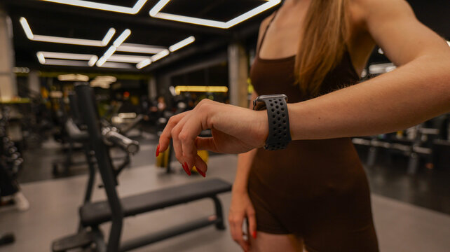Woman checking her smartwatch during a workout session in a modern gym