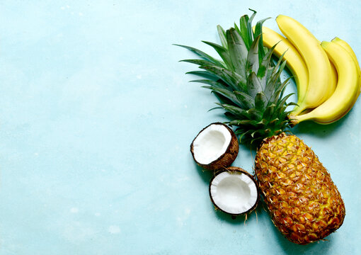 Different types of exotic fruits : pineapple, coconut, banana, orange, persimmon and pomegranate.