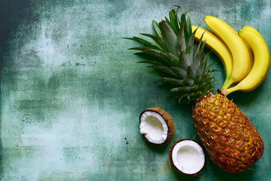 Different types of exotic fruits : pineapple, coconut, banana, orange, persimmon and pomegranate.