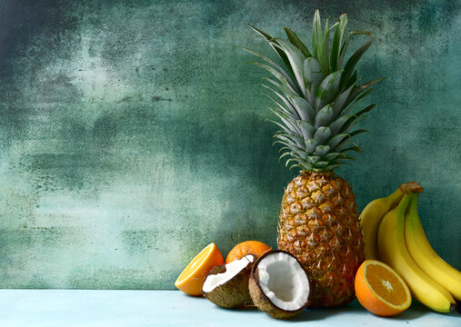 Different types of exotic fruits : pineapple, coconut, banana, orange, persimmon and pomegranate.