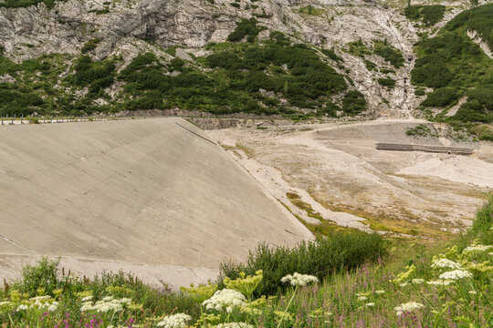 Canazei, Italy. Lago di Fedaia reservoir showing exposed basin and concrete dam structure during drought and low water levels
