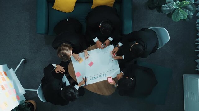Top down view of business people hands making scrum task board to manage workflow in workplace. Diverse marketing team drawing a line and use colorful stick notes to work on kanban. Directorate.