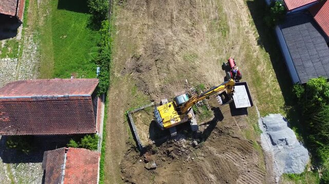 Aerial drone view of excavator loading concrete debris into tractor trailer