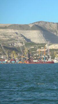 Harbor cargo ship entering Port of Novorossiysk with mountains 