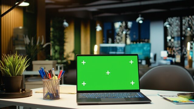 Empty corporate workspace with a green screen laptop in a multinational company late at night includes a boardroom setup with reports strategy icons and projections ready for development.