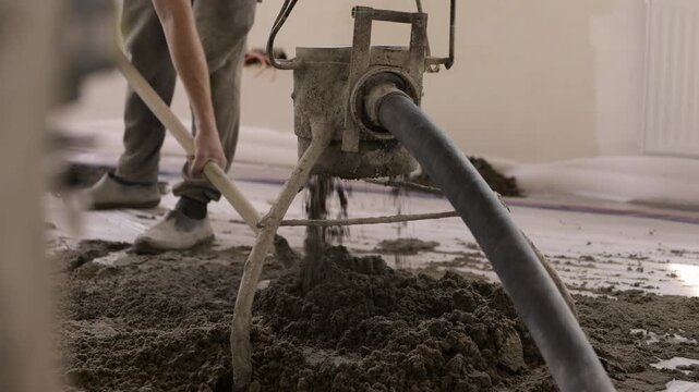 Fresh floor screed pumped and spread during apartment construction