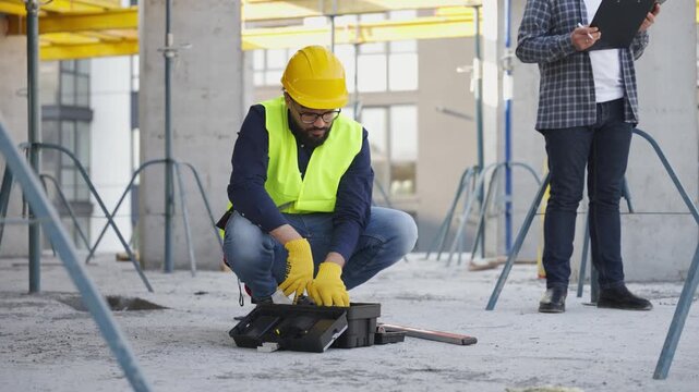 Construction worker preparing tools under supervisor's watch