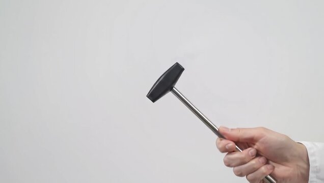 Close-up of doctor's hand holding and moving a neurological reflex hammer for medical examination