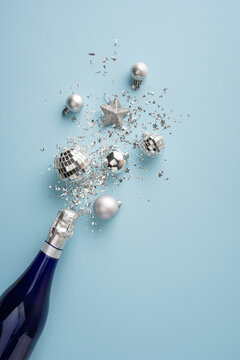 Happy New Year 2027 celebration with champagne bottle, silver ornaments and confetti on vertical blue background