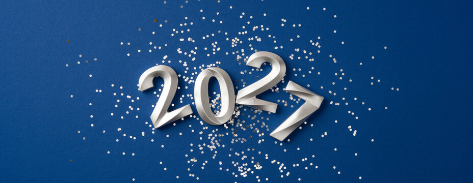 Happy New Year 2027 celebration with silver numbers and confetti on blue banner background