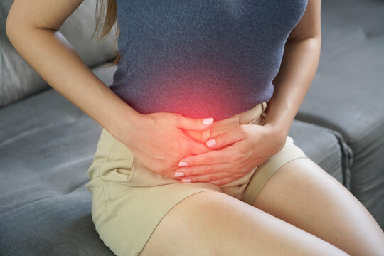 Unidentified woman holding her lower abdomen experiencing ovulation pain or mittelschmerz