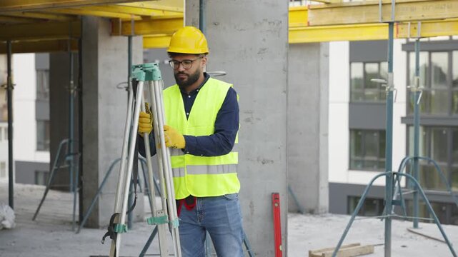 Surveyor engineer setting up a theodolite on a tripod at a construction site