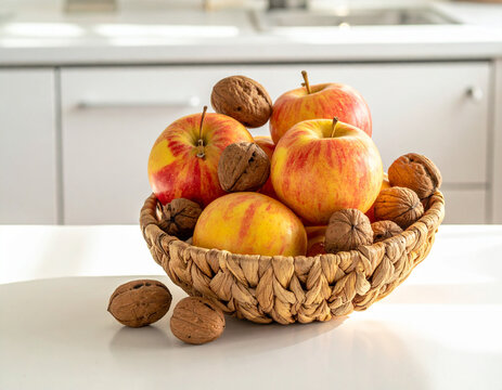 Handwoven baskets filled with fresh apples and walnuts create a seasonal still life on a clean modern kitchen island surface.