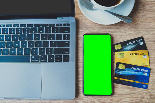 Credit card of laptop computer, smartphone empty screen and coffee cup on wooden background,Online banking Concept,Green screen