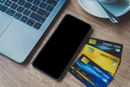 Credit card of laptop computer, smartphone empty screen and coffee cup on wooden background,Online banking Concept