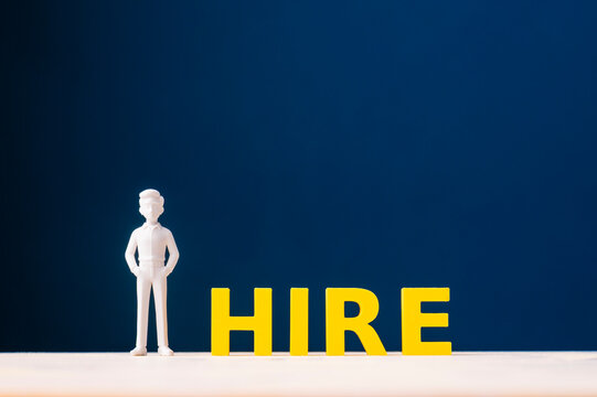 Hiring and recruitment concept with businessman standing beside HIRE letters