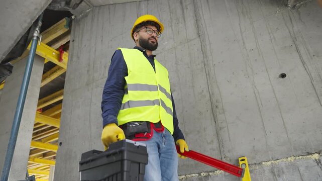 Construction worker walking on building site with toolbox